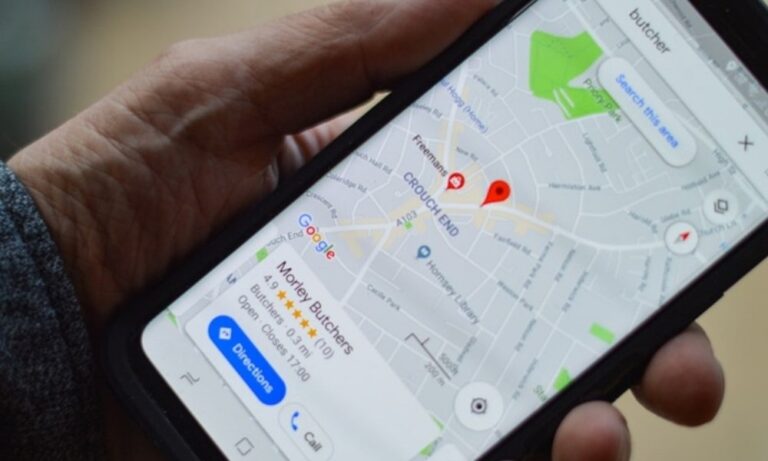 A hand holding a smartphone displaying a Google map with a local business search visible